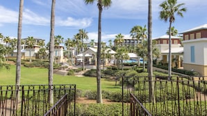 Un resort con varias construcciones, palmeras y un césped cuidado.