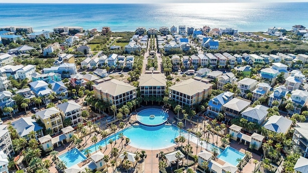 Un complejo turístico con varias edificaciones, una piscina central y vistas al océano.
