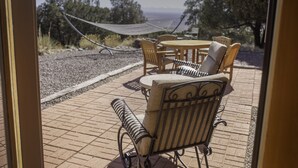 An outdoor patio with a round table and chairs, a hammock, and a view of the ocean. - Lovely Home in Crestone - Great Views! (Crestone)