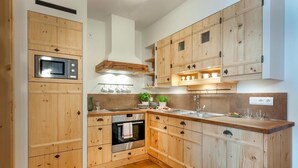 A kitchen with wooden cabinets, a built-in oven, a microwave, and a sink. - Ferienwohnung "Scheunentor", 63 qm Obergeschoss, 2 separate Schlafzimmer (Höslwang)