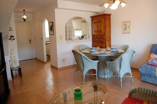 A dining area with wicker chairs, a round table, and a wooden cabinet.