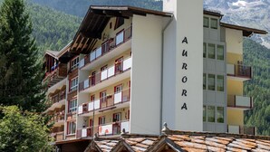 Ett hotell i flera våningar som heter ”AURORA”, med balkonger och utsikt över snöklädda berg.