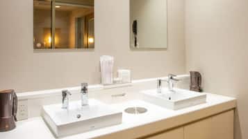 Un baño con dos lavamanos, un espejo y un dispensador de toallas.