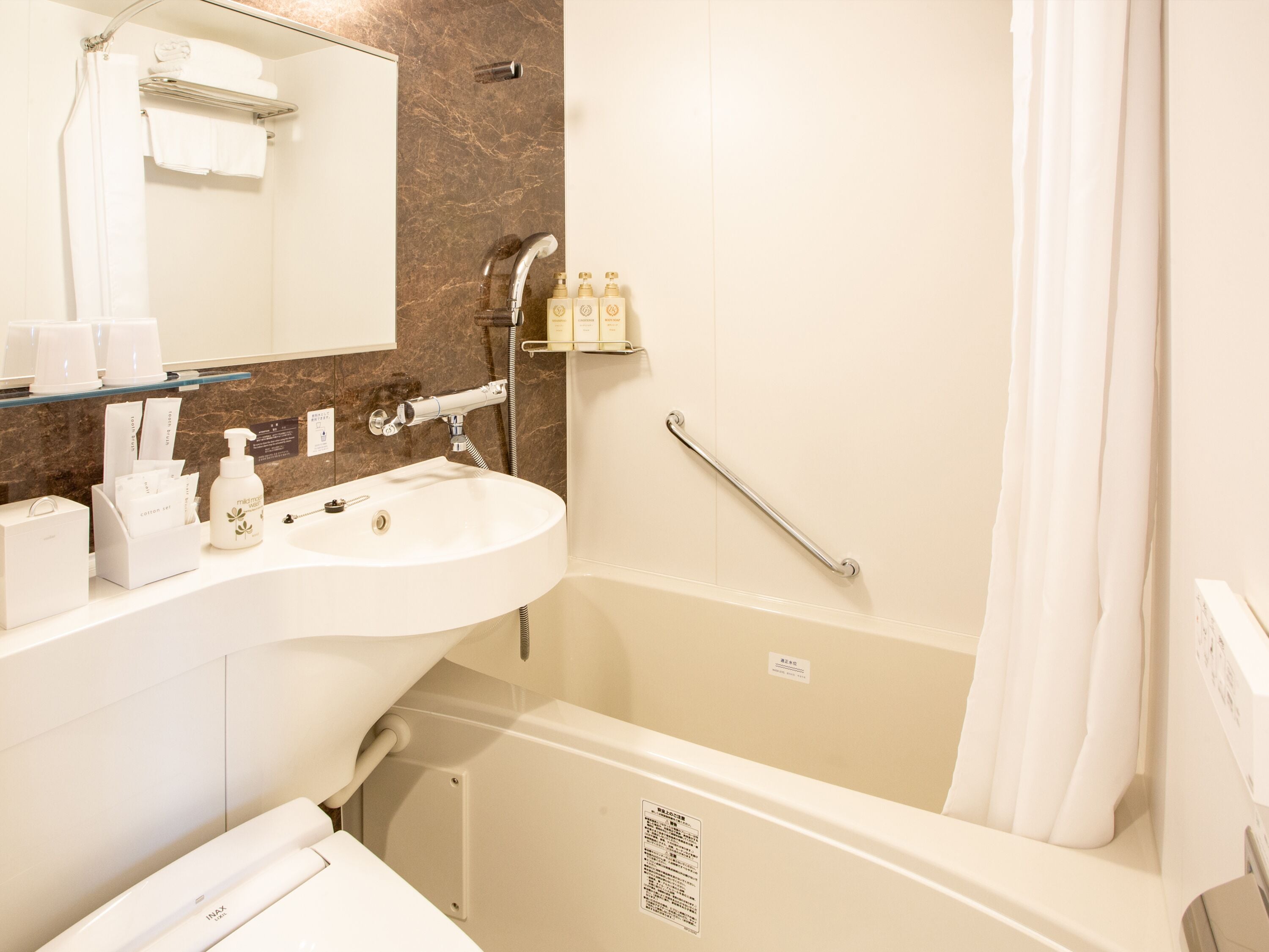 A bathroom with a white sink, a mirror, a shower with a grab bar, and a bathtub.