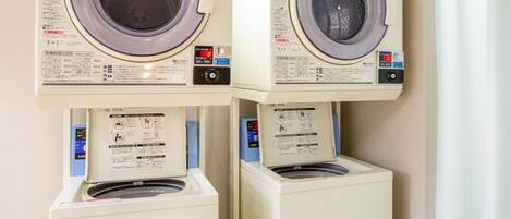 Two stacked front-loading washing machines with control panels and safety instructions.