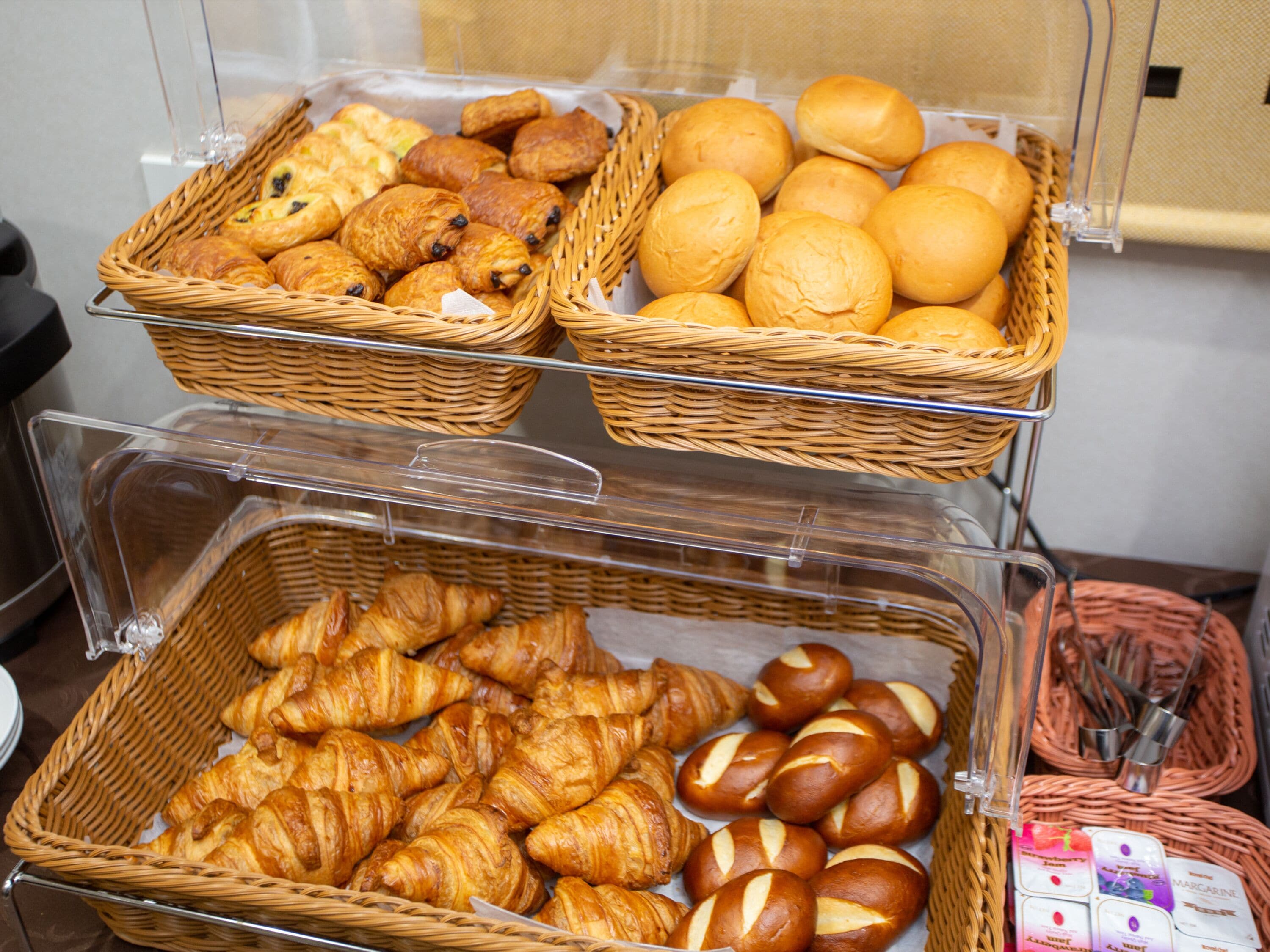 Un expositor de panadería con diversos productos horneados en cestas de mimbre.