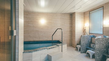 A modern spa with a large hot tub, seating area, and a tiled floor.