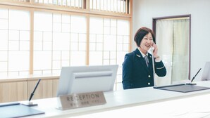 A reception desk with a sign reading "RECEPTION" and a computer monitor. - Kuretake Inn Premium Ogakiekimae (Ogaki)