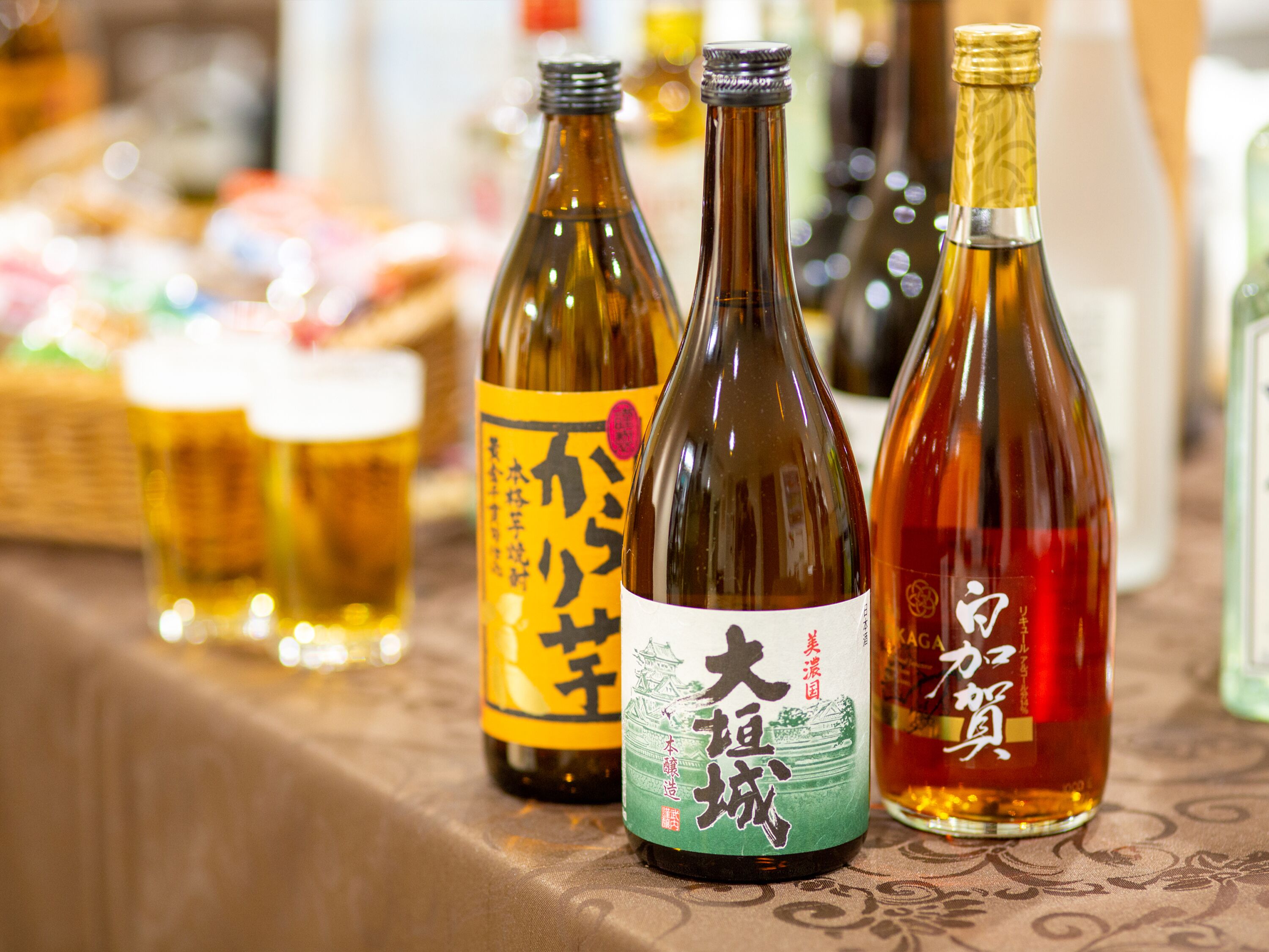 A selection of bottles with labels, likely containing beverages, arranged on a table.