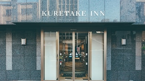 The entrance to the Kuretake Inn with a modern design, featuring glass doors and a stone facade. - Kuretake Inn Premium Ogakiekimae (Ogaki)