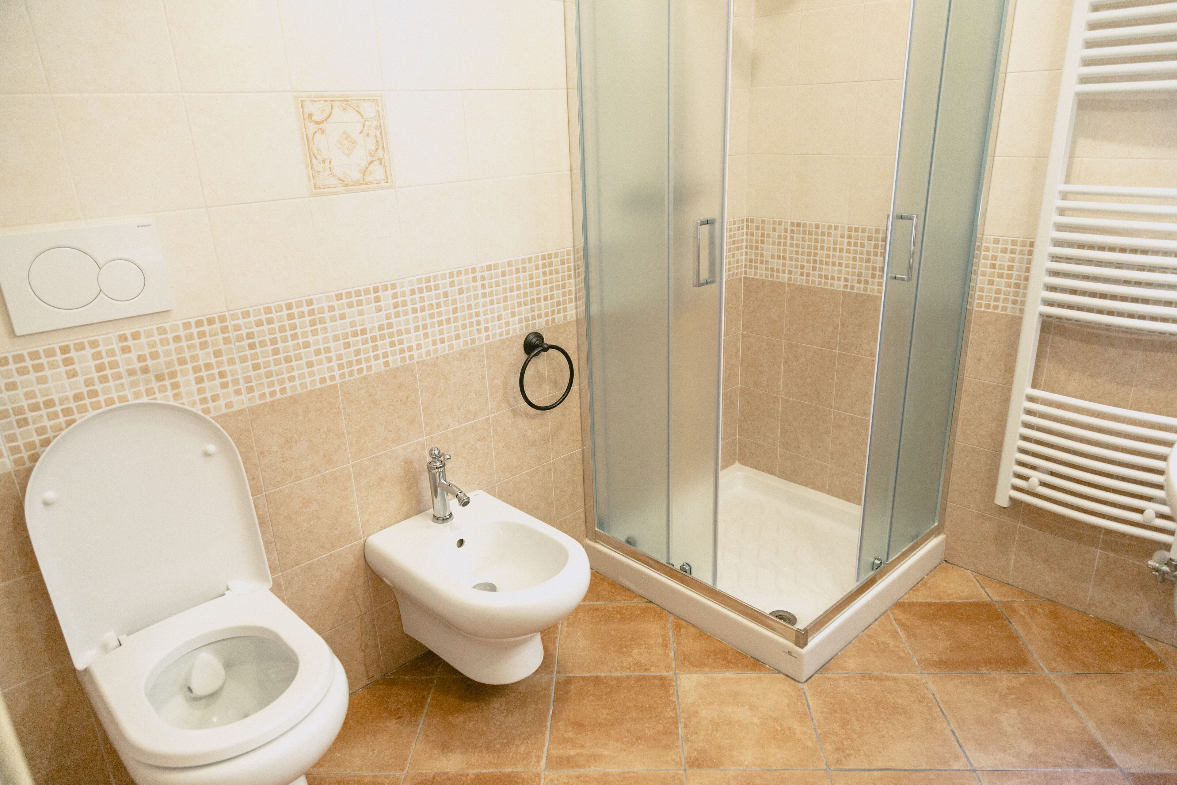 Une salle de bain équipée de toilettes, d’un bidet et d’une douche à parois de verre.