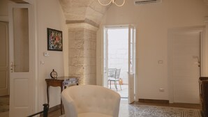 Un dormitorio con cama, una silla, un escritorio y una puerta que da a un balcón.