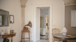 Una habitación con una mesa de madera, una silla, una mesita auxiliar y un espejo en la pared.