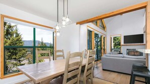 A modern interior with a dining area, a sofa, and a TV. - Townhome w/ hot tub & AC near village (Whistler)