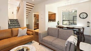 A modern living room with a sofa, a coffee table, and a dining area with a table and chairs. - Slopeside retreat w/ hot tub & garage (Whistler)
