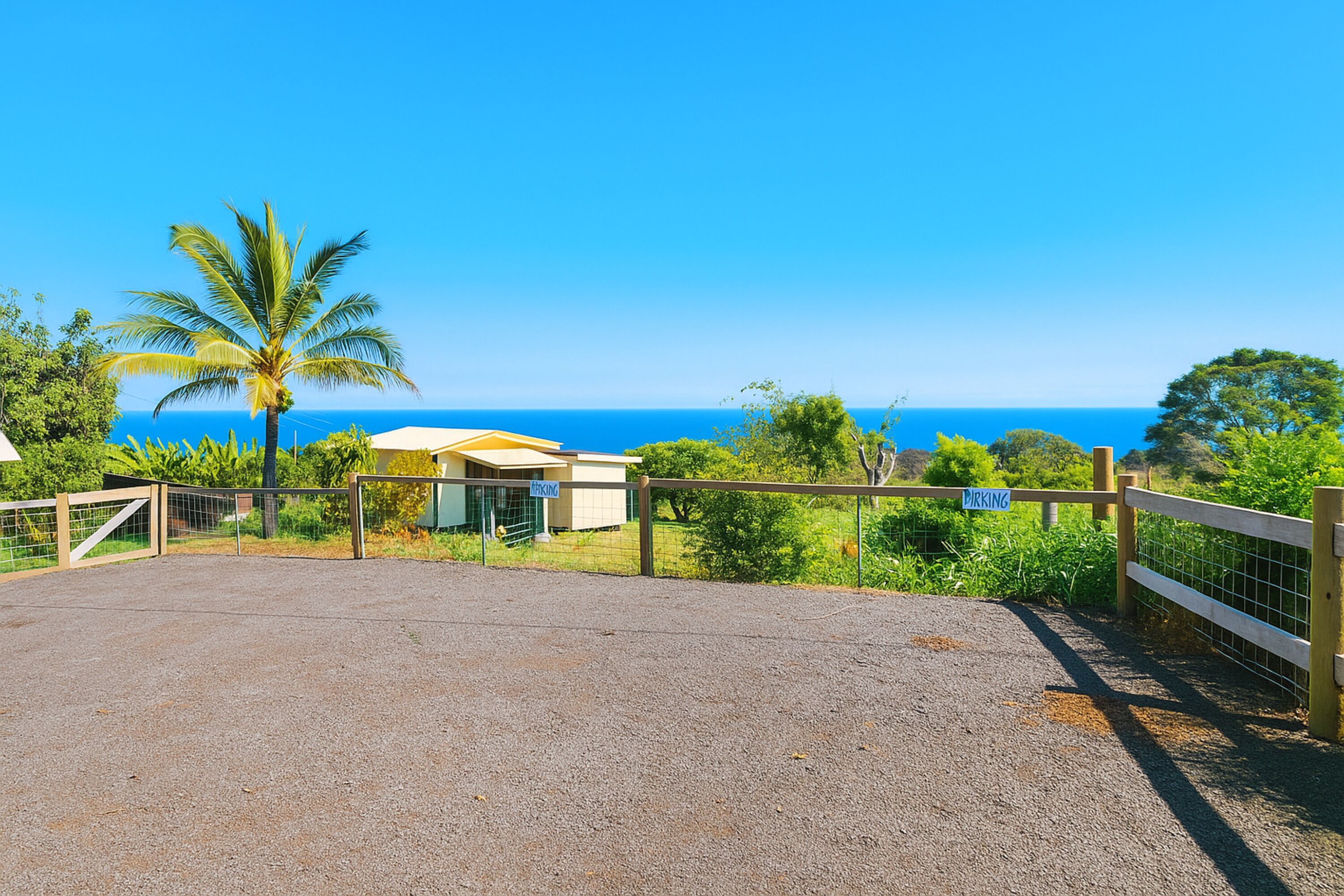 A gravel parking area with a wooden fence, a small building labeled "PARKING," and a view of the ocean.