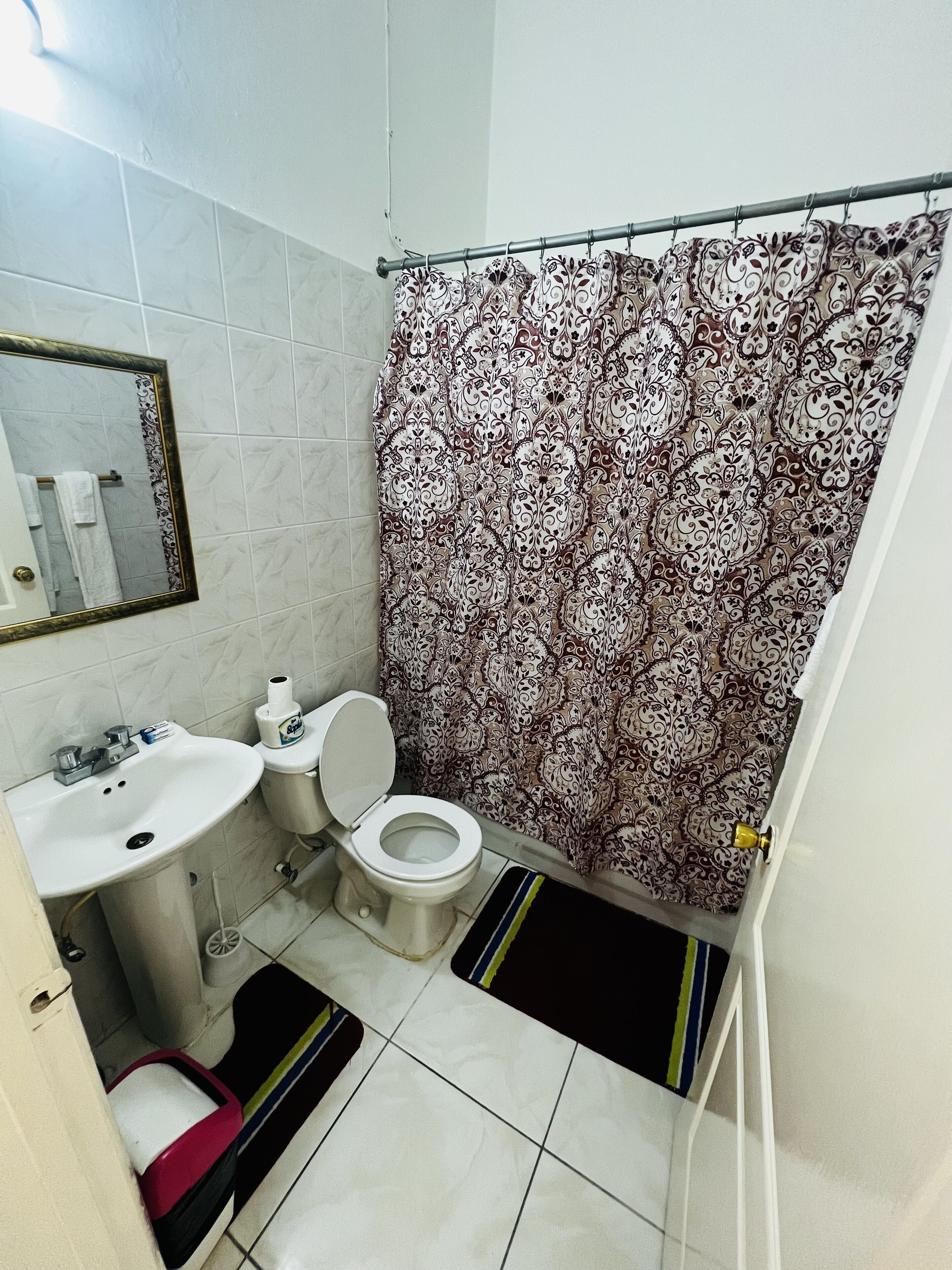 A bathroom with a toilet, sink, and shower curtain.