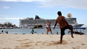 Ein Strand mit einem Kreuzfahrtschiff im Hintergrund.