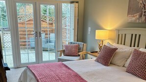 A hotel room with a large bed, a chair, a lamp, and a view of the outside. - Blenkinsopp Castle Inn (Brampton)