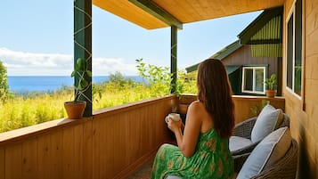 A woman sitting on a wicker chair on a wooden deck with a view of the ocean.