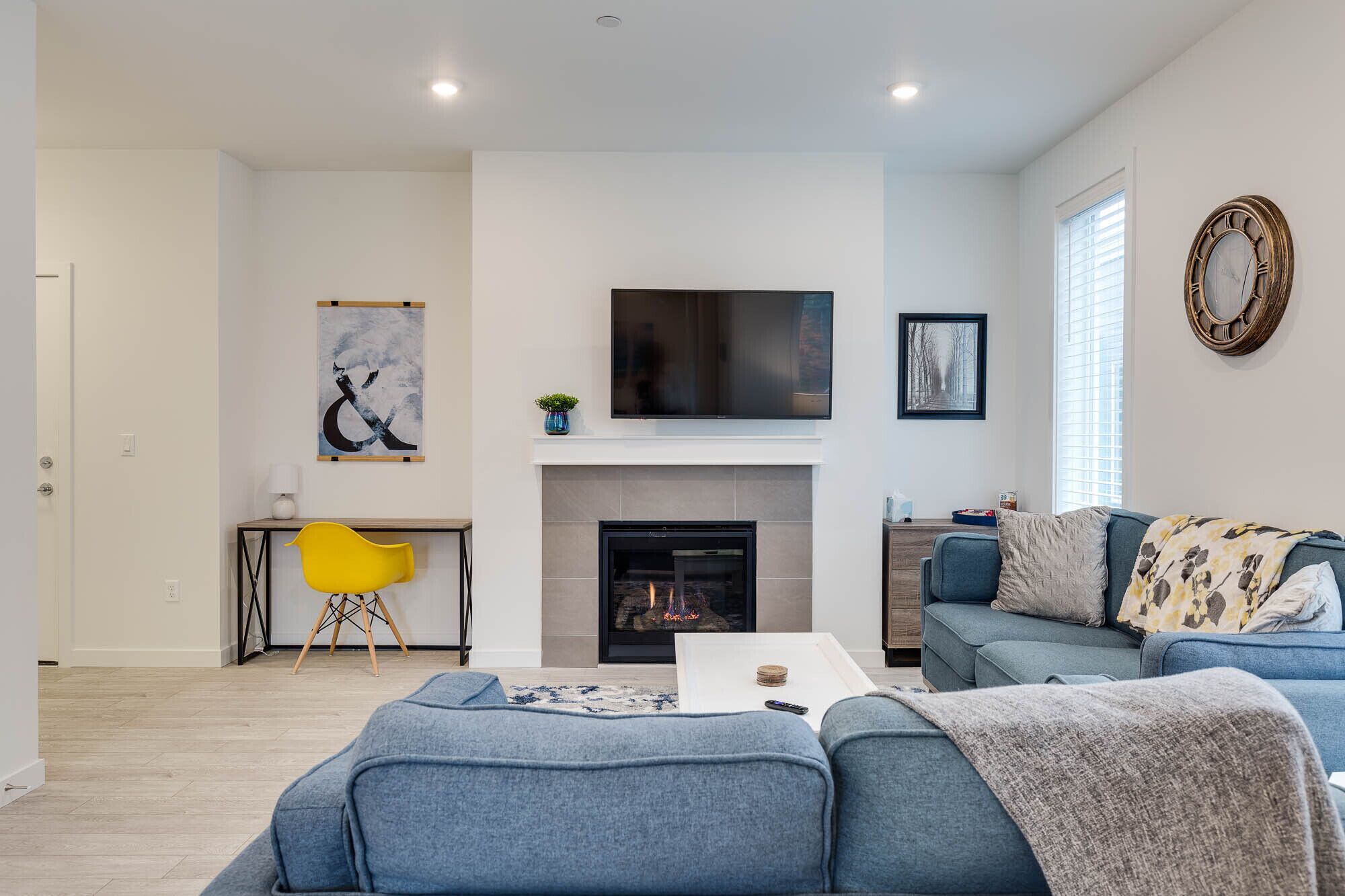 A modern living room with a fireplace, a flat-screen TV, and a sofa.