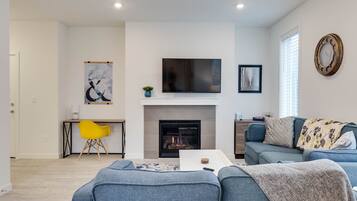 A modern living room with a fireplace, a flat-screen TV, and a sofa.