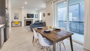 A modern kitchen with a dining area, a fireplace, and a balcony with a view of the building.