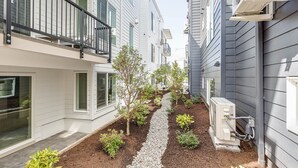 A narrow pathway flanked by residential buildings with balconies and small gardens.