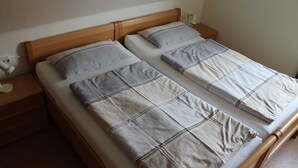 Un lit double avec une tête de lit en bois et deux tables de chevet, chacune équipée d’une lampe.