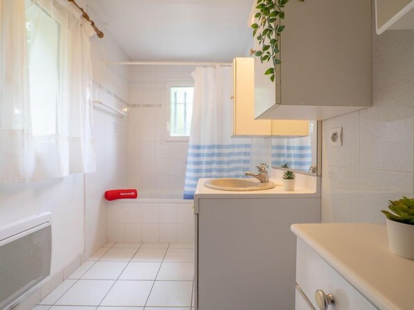 Een badkamer met een wit wastafel, een spiegel en een douche.