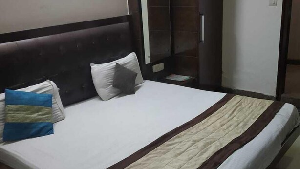 A hotel room with a large bed, a wardrobe, and a mirror. - ADB Rooms Hotel Chander Palace (New Delhi)