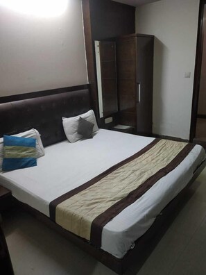 A hotel room with a large bed, a wardrobe, and a mirror. - ADB Rooms Hotel Chander Palace (New Delhi)