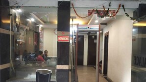 A hotel entrance with a 'NO PARKING' sign, a glass door, and a chair outside. - ADB Rooms Hotel Chander Palace (New Delhi)