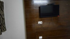 A wall-mounted television with a cable connected to a power outlet. - ADB Rooms Hotel Chander Palace (New Delhi)