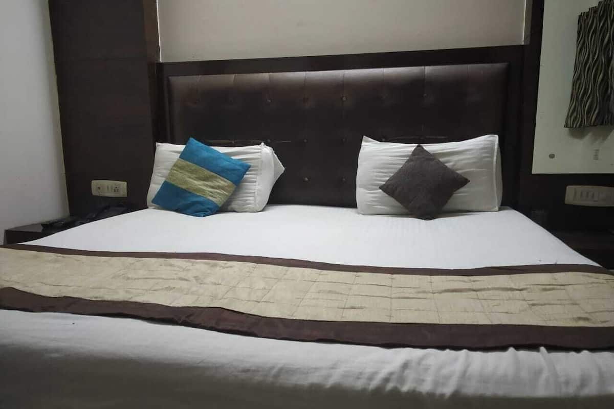 A neatly made bed with a dark headboard, white bedding, and two pillows.