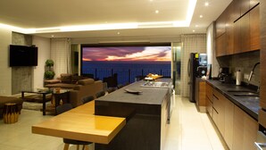 A modern kitchen with a large island, a dining area with a view, and a flat-screen TV mounted on the wall. - ★ 15th Floor Grand Venetian ★ (Puerto Vallarta)