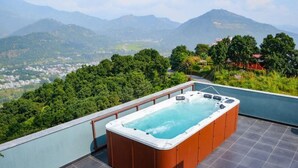 Un jacuzzi en una azotea con una vista panorámica de las montañas.