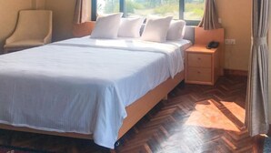 Una habitación de hotel con una cama grande, una mesita de noche con un teléfono y una silla.