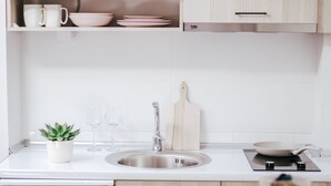 A modern kitchen with white cabinetry, a dishwasher, a sink, and a wooden table. - White and Wood Boutique Hotel (Bitola)