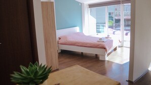A bedroom with a bed, a wooden table, and a potted plant. - White and Wood Boutique Hotel (Bitola)