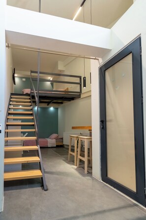 A compact living space with a bunk bed, a staircase, a dining area, and a door. - White and Wood Boutique Hotel (Bitola)