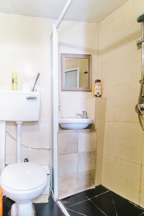 A bathroom with a toilet, sink, and shower.