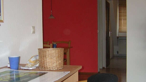 Un'area pranzo con un tavolo in legno, sedie, un cesto e un lampadario.