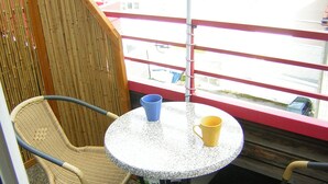 Un piccolo balcone con sedie in vimini, un tavolino rotondo e due tazze.