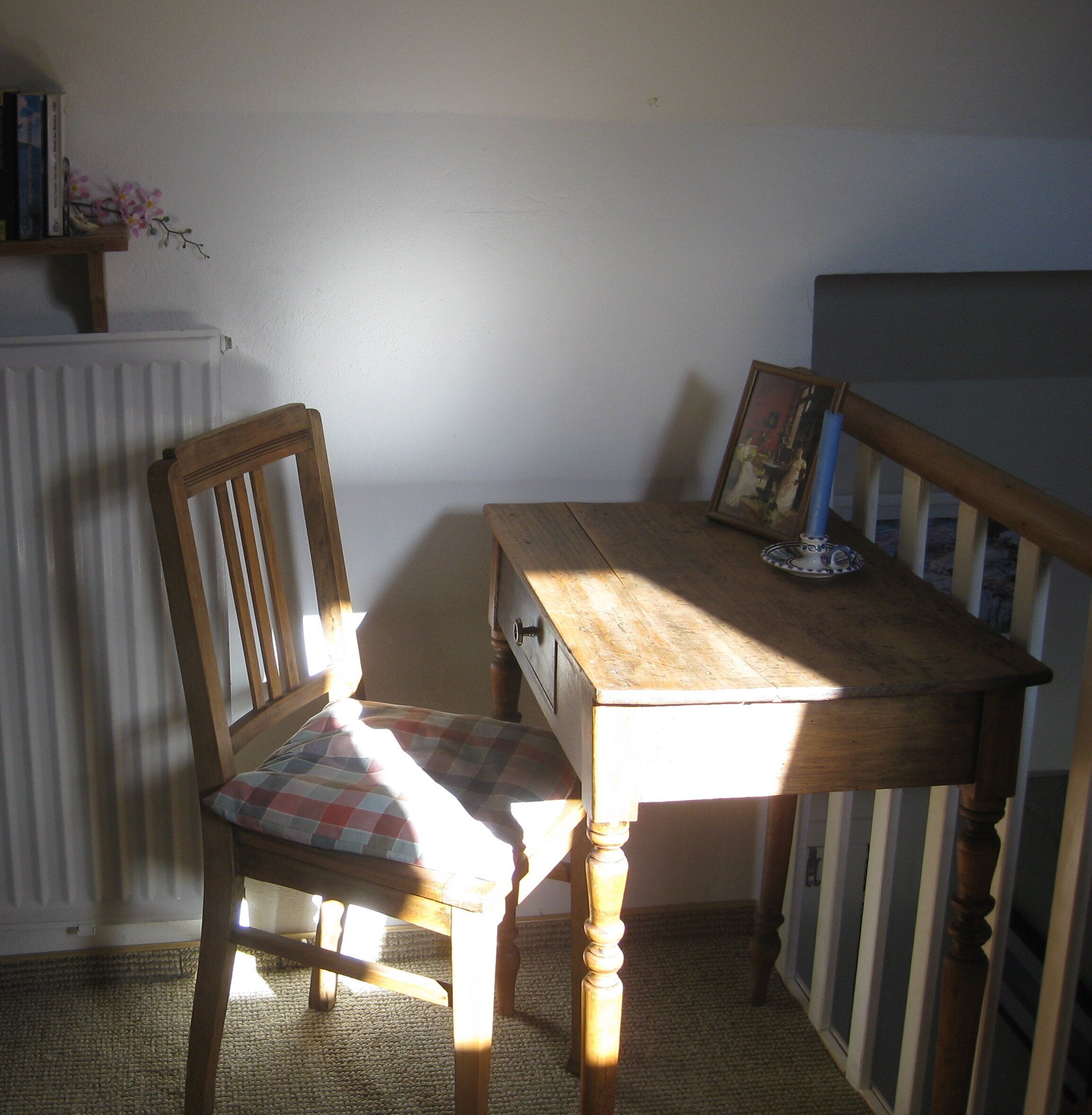 Une table à manger en bois, une chaise, un radiateur et un tableau encadré accroché au mur.
