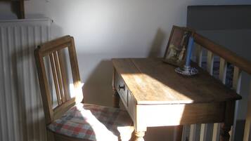Une table à manger en bois, une chaise, un radiateur et un tableau encadré accroché au mur.