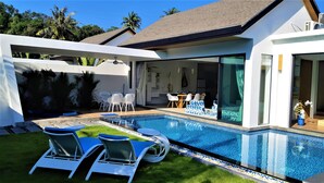 Ein modernes Haus mit Swimmingpool, Sitzgelegenheit im Freien und einer Terrassenfläche.