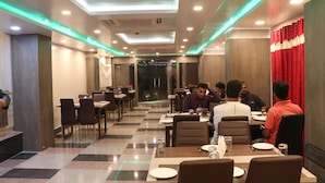 A restaurant with a checkered floor, multiple tables, and chairs. - Hotel Nandini (Baharampur)