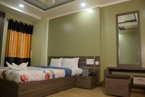 A hotel room with a bed, bedside tables, a mirror, and a nightstand. - Hotel Nandini (Baharampur)