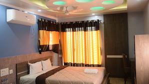 A hotel room with a bed, curtains, a ceiling fan, and an air conditioning unit. - Hotel Nandini (Baharampur)